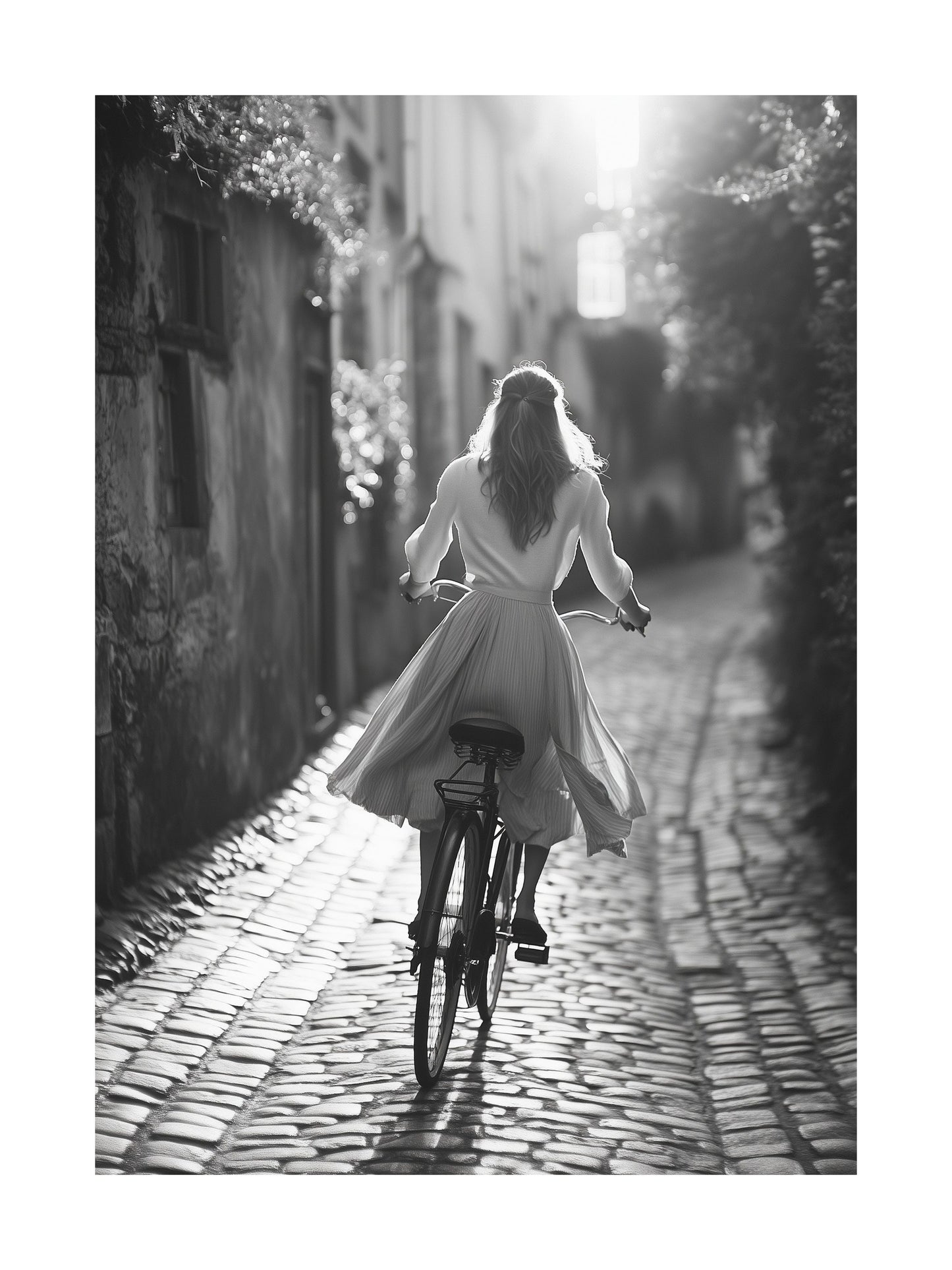 Black and white photo of a woman riding a bicycle on cobblestone street