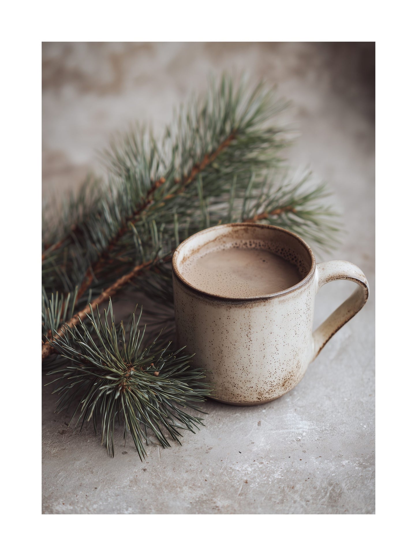 Ceramic mug of hot cocoa placed beside pine branches on a textured surface.