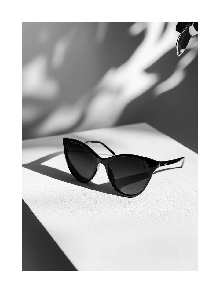 Black sunglasses on a white tabletop with dramatic shadows